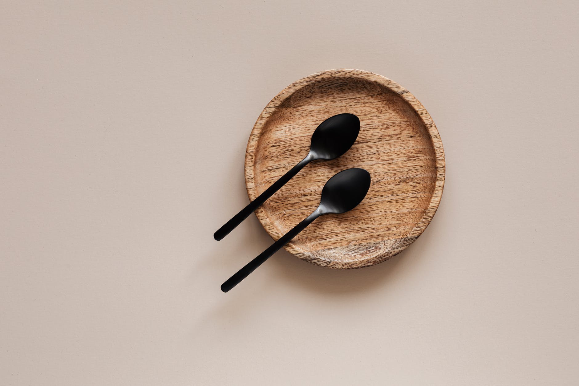 wooden plate with metal spoons on beige background